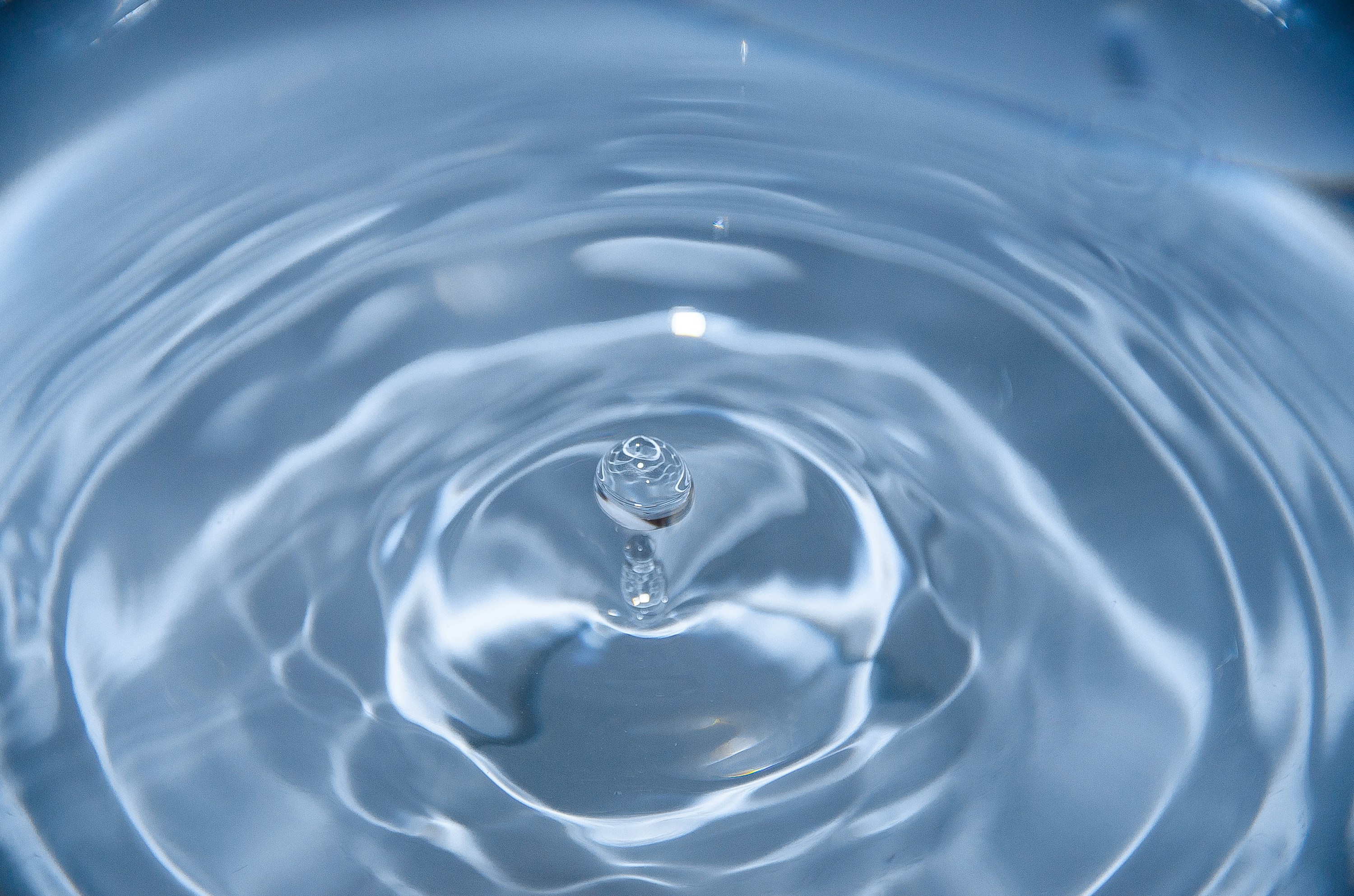 Goccia d'acqua che rimbalza sulla superficie formando cerchi concentrici
